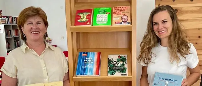 Zwei Frauen halten jeweils ein Buch in der Hand und lächeln in die Kamera.