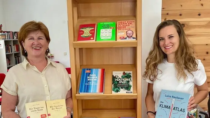 Zwei Frauen halten jeweils ein Buch in der Hand und lächeln in die Kamera.