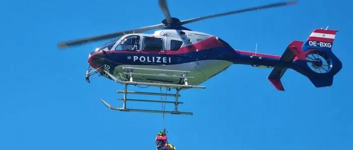 Das Bild zeigt eine Person, die an einem Tau am Polizeihubschrauber hängt