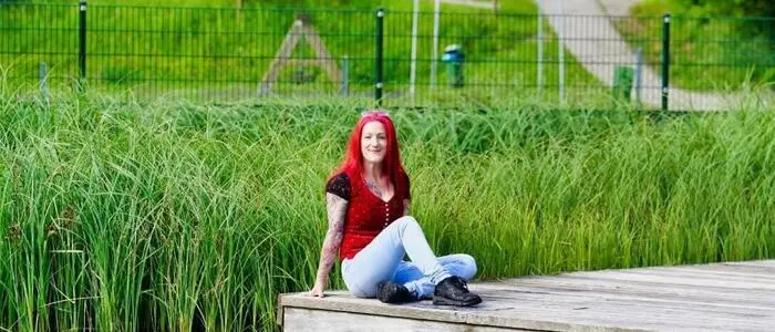 Eine Frau sitzt auf einem Steg an einem See