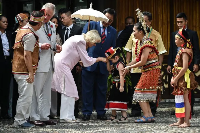 Der in einen hellen Anzug mit Krawatte gekleidete britische Kronprinz wirkte hoch konzentriert, als er ein Auge schloss, in das auf einem Ast abgelegte lange, dünne Holzrohr blies und einen Pfeil ins Ziel schoss. 