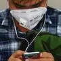 (FILES) In this file photo a man wearing a facemask amid concerns over the spread of the COVID-19 coronavirus uses his smart phone while travelling on a suburban train in Mumbai on March 11, 2020. - Digital surveillance and smartphone technology may prove helpful in containing the coronavirus pandemic -- but some activists fear this could mean lasting harm to privacy and digital rights. From China to Singapore to Israel, governments have ordered electronic monitoring of their citizens' movements in an effort to limit contagion. In Europe and the United States, technology firms have begun sharing "anonymized" smartphone data to better track the outbreak. (Photo by Indranil MUKHERJEE / AFP)