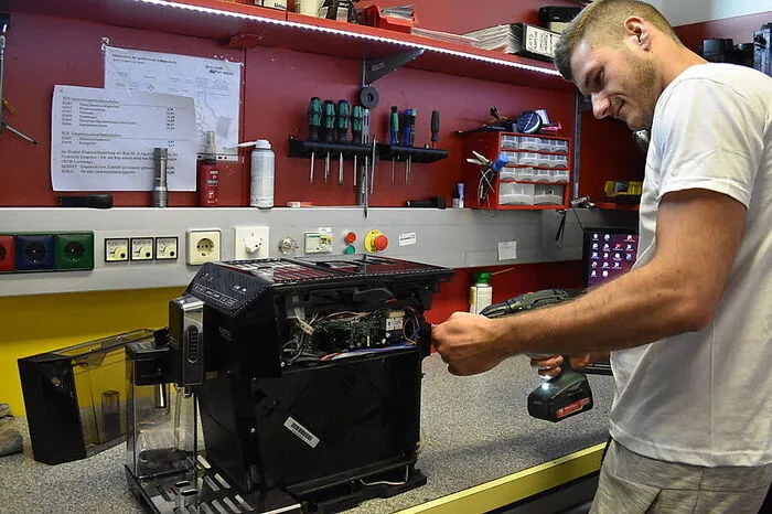 Mitarbeiter Martin Simicic repariert in der Werkstatt eine defekte Kaffeemaschine