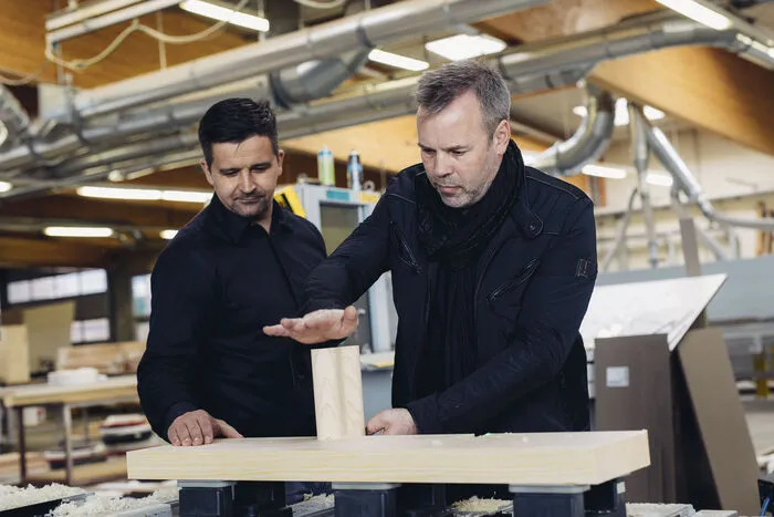 Guido Strohecker (rechts im Bild) in der Tischlerei, in der die Holzpfosten gefertigt werden. Rund 40 Zentimeter dick sind die Holzmauern, extra Dämmung gibt's keine. 