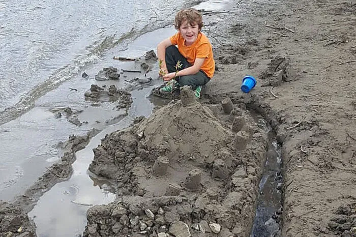 Zum Zeitvertreib baut Matteo (5) eine Sandburg bei der St. Michaeler Murinsel. Er grüßt seine Freunde aus dem Kindergarten 1 in St. Michael.