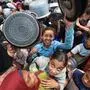 Palestinians gather for a hot meal at a food distribution point in the Nuseirat camp for refugees in the central Gaza Strip on May 21, 2025. Gazans waited desperately for vital supplies on May 21 after Israel said it let in dozens of UN trucks but faced mounting international pressure to increase the aid flow and abandon its intensified military campaign. (Photo by Eyad BABA / AFP)