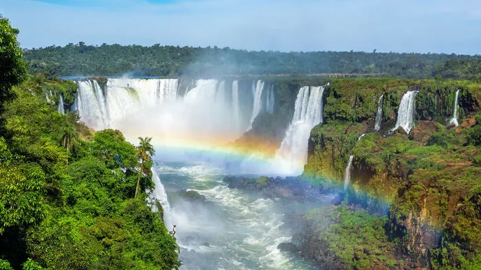 In einem etwa drei Kilometer großen Bogen stürzt der Rio Iguaçu in die Tiefe und hinterlässt einen Sprühnebel in Regenbogenfarben. Einen spektakulären Blick auf die Wasserfälle hat man nicht nur im Parque Nacional do Iguaçú, sondern auch auf argentinischer Seite – mit dem Zug geht es zum „Teufelsrachen“ (Gargant adel Diablo ).