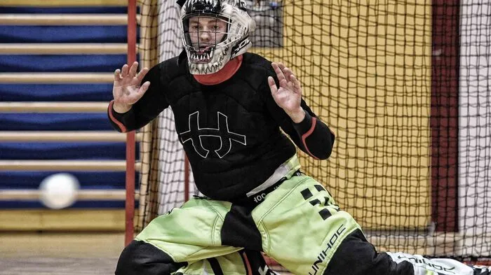 Auf Knien versucht der Floorball-Goalie mit Händen und Füßen den Ball abzuwehren