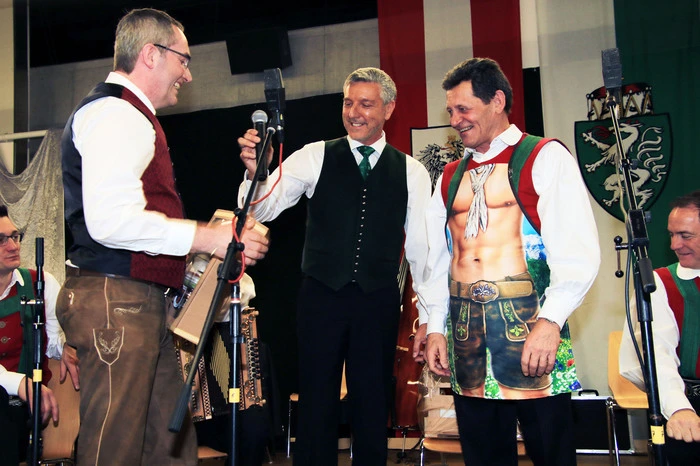Stallhofens Bürgermeister Franz Feirer (links) und Organisator Josef Strohmeier (Mitte) überreichten an den Fernseh-Liebling einen Geschenkkorb mit kulinarischen Schmankerln aus der Region sowie kunstvolle Glasbecher aus dem Glasmuseum Bärnbach. Als ganz besonderes Erinnerungsgeschenk erhielt Franz Posch eine ulkige Schürze, die der Volksmusikant auch gleich anprobierte.
