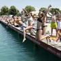 Kinder springen vom Steg in den See.