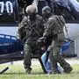 Members of a special police unit escort a man suspected to be responsible for the Solingen knife attack from a helicopter to the office of the Federal Prosecutor in Karlsruhe, southern Germany, on August 25, 2024. Police arrested the suspect in a raid at a hostel for asylum seekers on August 24, 2024, not far from the scene of the random attack during festivities to celebrate the 650th anniversary of Solingen, western Germany. Authorities said that the Syrian man had given himself up and confessed to killing three people and wounding several others in a knife rampage at a street festival. (Photo by THOMAS KIENZLE / AFP)