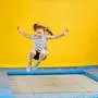 Happy child girl jumping on trampoline in fitness center