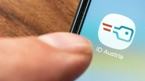 Ein Finger tippt auf das App-Symbol „ID Austria“ auf dem Display eines Smartphones.
