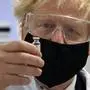 Britain's Prime Minister Boris Johnson holds a vial of the Oxford/AstraZeneca vaccine Covid-19 candidate vaccine, known as AZD1222, at Wockhardt's pharmaceutical manufacturing facility in Wrexham, Wales, Monday, Nov. 30, 2020. (Paul Ellis/PA via AP)
