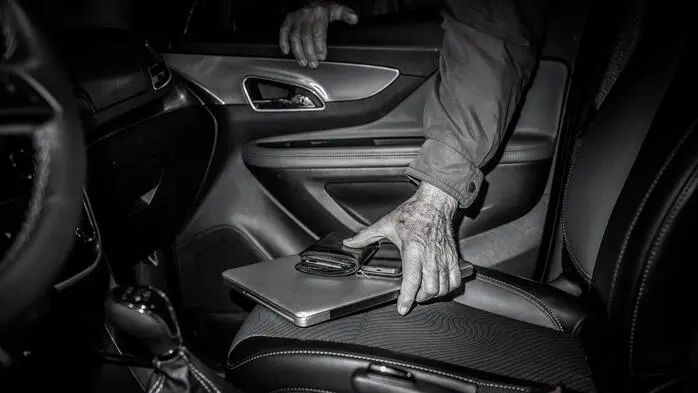 Ein Mann stiehlt ein Notebook aus einem Auto