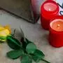 Das Bild zeigt zwei brennende Kerzen und eine gelbe Rose