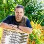 Mann steht mit einer Schautafel mit Schmetterlingen im Garten | Manuel Vilgut, Vorstand der Fachgruppe Entomologie (Insektenkunde) des Naturwissenschaftlichen Vereins Kärnten