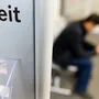 In einem Raum beim Arbeitsmarktservice sitzt eine Person in der Kameraunschärfe