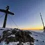 Ein Gipfelkreuz und ein Sendemasten auf dem Gipfel des Dobratsch