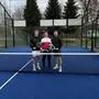 Drei Männer stehen auf einem Padeltennis-Platz, sie halten jeweils einen Schläger in der Hand.