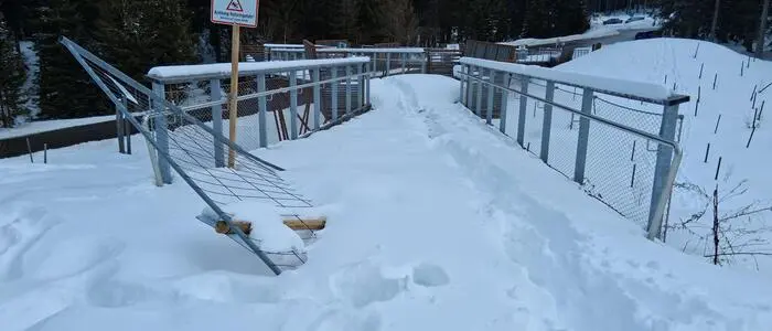 Eine Aussichtsplattform im Winter. Es liegt viel Schnee und man sieht, dass ein Gitter kaputt ist
