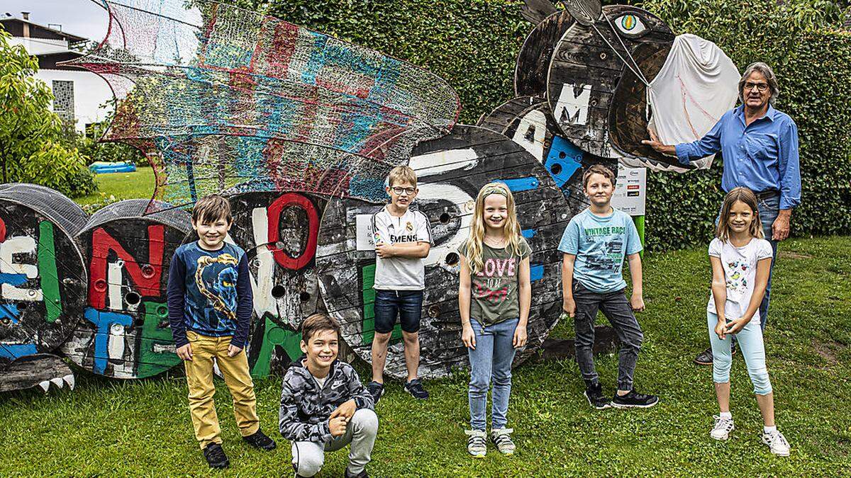 Schuldirektor Christian Zeichen mit Schülern vor der symbolischen Holzskulptur „Lindfried“ (mit Mundschutz).  