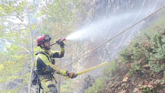 Ein Feuerwehrmann beim Löschen in einem sehr steilen Hang
