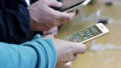 FILE - In this Sept. 22, 2017, file photo, customers look at iPhone 8 and iPhone 8 Plus phones at an Apple Store in San Francisco. Retailers are taking back some control of the store experience with smart phone app features that let customers do things like scan and pay and download digital maps. It marks a big difference from just a few years ago when retailers viewed the smart phone as their enemy - customers often whipped out their device to compare prices online and walked out of the store to buy elsewhere. (AP Photo/Jeff Chiu, File)