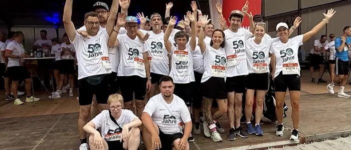 Mehrere Menschen in Sportbekleidung lächeln und jubeln in die Kamera.