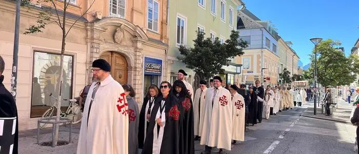 Männer und Frauen mit langem Umhang in einer Innenstadtstraße