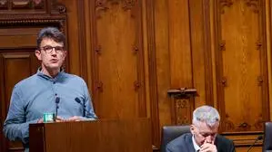 Neos-Gemeinderat Philipp Pointner hinter Rednerpult im Gemeinderat in Graz, daneben Finanzstadtrat Manfred Eber (KPÖ) auf der Regierungsbank