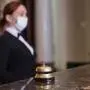 the hotel staff serves guests in medical masks