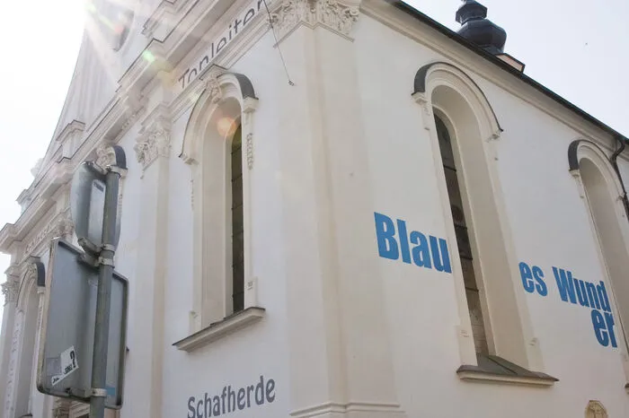 Nach einer Idee von Gustav Troger schmücken seither Begriffe in unterschiedlichen Farben die Kirchenfassade. "Maikäfer flieg" ist hier ebenso zu lesen wie "science fiction".