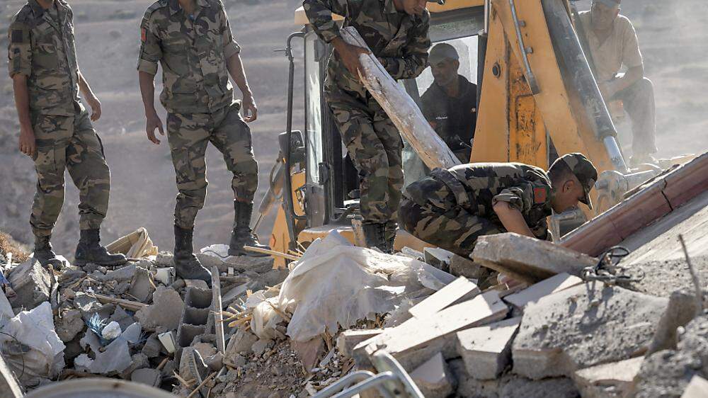 Die Rettungskräfte graben sich mit schwerem Gerät durch die Trümmer der eingestürzten Häuser