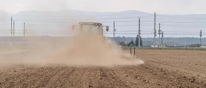 Traktor auf trockenem Feld, Staubentwicklung