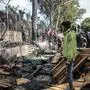 Refugees and migrants stand near a burnt area after a fire broke out in the camp of Moria in the island of Lesbos, on March 16, 2020. (Photo by Manolis Lagoutaris / AFP)