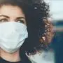 Lovely curly haired caucasian lady protecting herself from viruses while wearing special mask