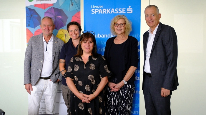 Menschen, die den Selbsthilfetag Osttirol organisieren oder an ihm beteiligt sind stehen in der Sparkasse Lienz