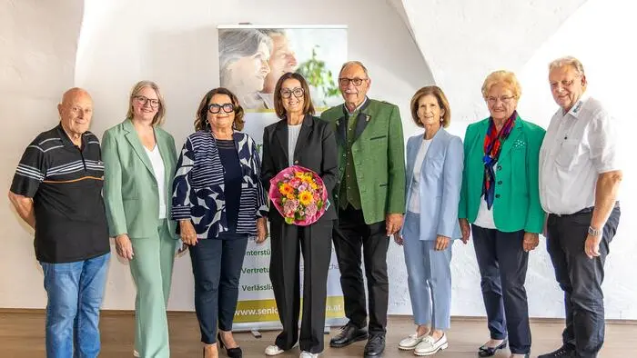 Einige Männer und Frauen lächeln für ein gemeinsames Foto in die Kamera.