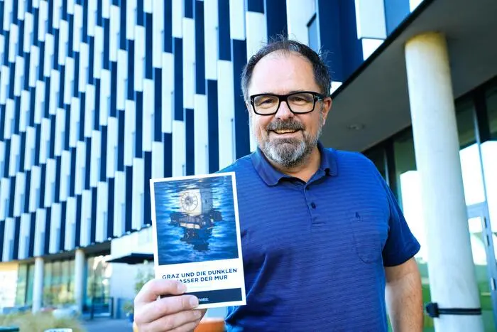 Ein Mann hält ein Buch in die Kamera.