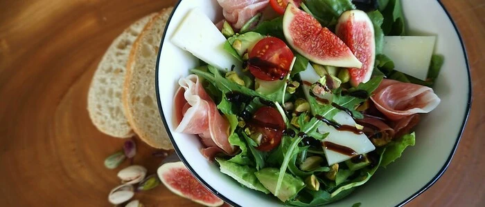 Römersalat kombiniert mit Käse, Schinken, gerösteten Pistazien und Feige