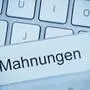 Eine Mappe für Akten im Hängeregister vor einer Computertastatur zum Thema: Mahnungen