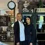 Zwei Frauen stehen in einem Lokal, im Hintergrund sieht man eine Uhr und Weinregale