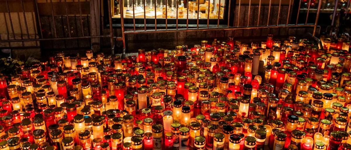 Viele brennende Kerzen stehen auf einem Platz in einer Stadt
