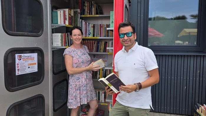 Ein Mann und eine Frau stehen vor einer Telefonzelle voller Bücher