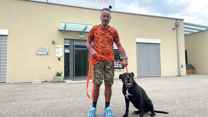 Zu sehen ist ein Mann, der einen Hund an der Leine hält