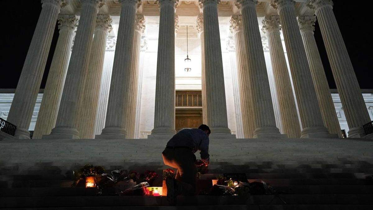 Im Andenken an die verstorbene Richterin Ruth Bader Ginsburg entzündet ein Mann vor dem Supreme Court in Washington eine Kerze