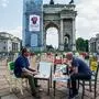 TOPSHOT - Restaurant owners Savino Tolentino (L) and Paolo Polli eat pizza among empty chairs displayed in front of the Arco della Pace monument on Piazza Sempione in Milan on May 6, 2020, as part of a protest of restaurant owners against the prolonged closures of their businesses, during the country's lockdown aimed at curbing the spread of the COVID-19 infection, caused by the novel coronavirus. (Photo by Piero CRUCIATTI / AFP)