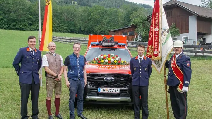 Fünf Männer vor einem Feuerwehrfahrzeug