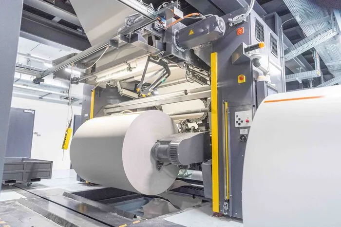 13 Meter pro Sekunde ab. Vier Rollenwechsler versorgen die vier Drucktürme mit Nachschub. Während des Betriebs wird die neue Bahn an die alte angeklebt. Die Maschine muss also nie stehen bleiben.